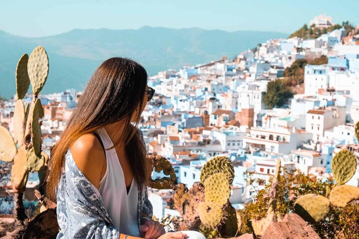 Una mujer parada en una colina mirando una ciudad.