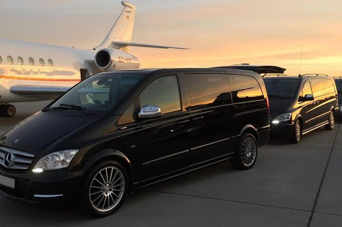 duas vans pretas estão estacionadas ao lado de um avião