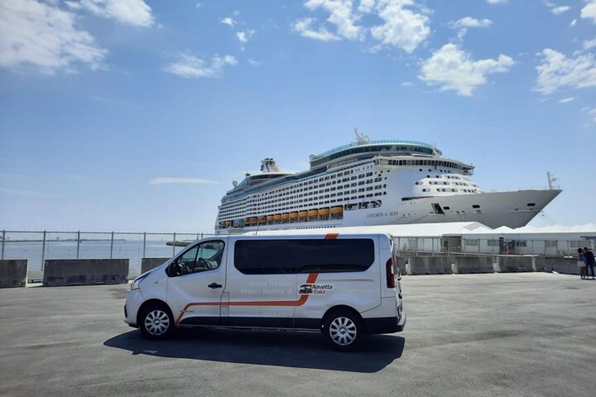 uma van branca estacionada em frente a um navio de cruzeiro