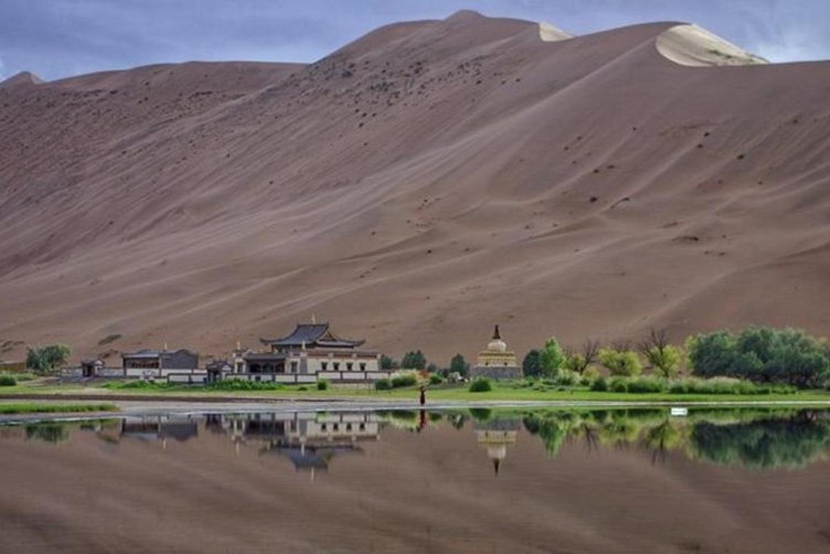 Una montaña al lado de un cuerpo de agua con un edificio.