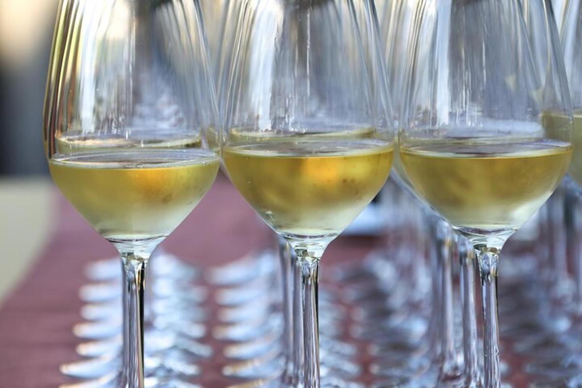Tres copas de vino llenas de vino blanco sobre una mesa