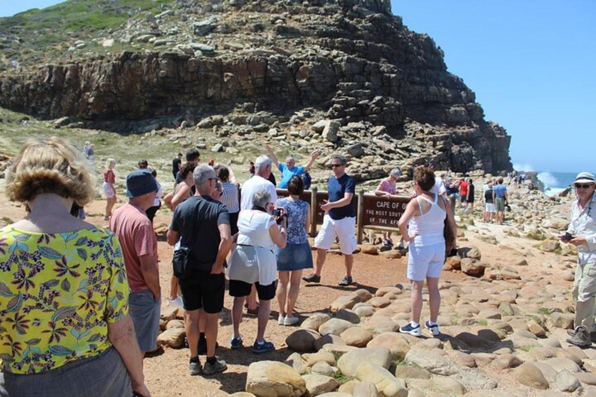 un gruppo di persone in piedi attorno a un cartello su una spiaggia