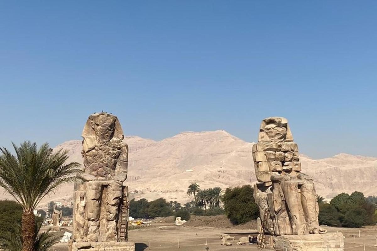 Dos estatuas de piedra en un desierto con montañas al fondo
