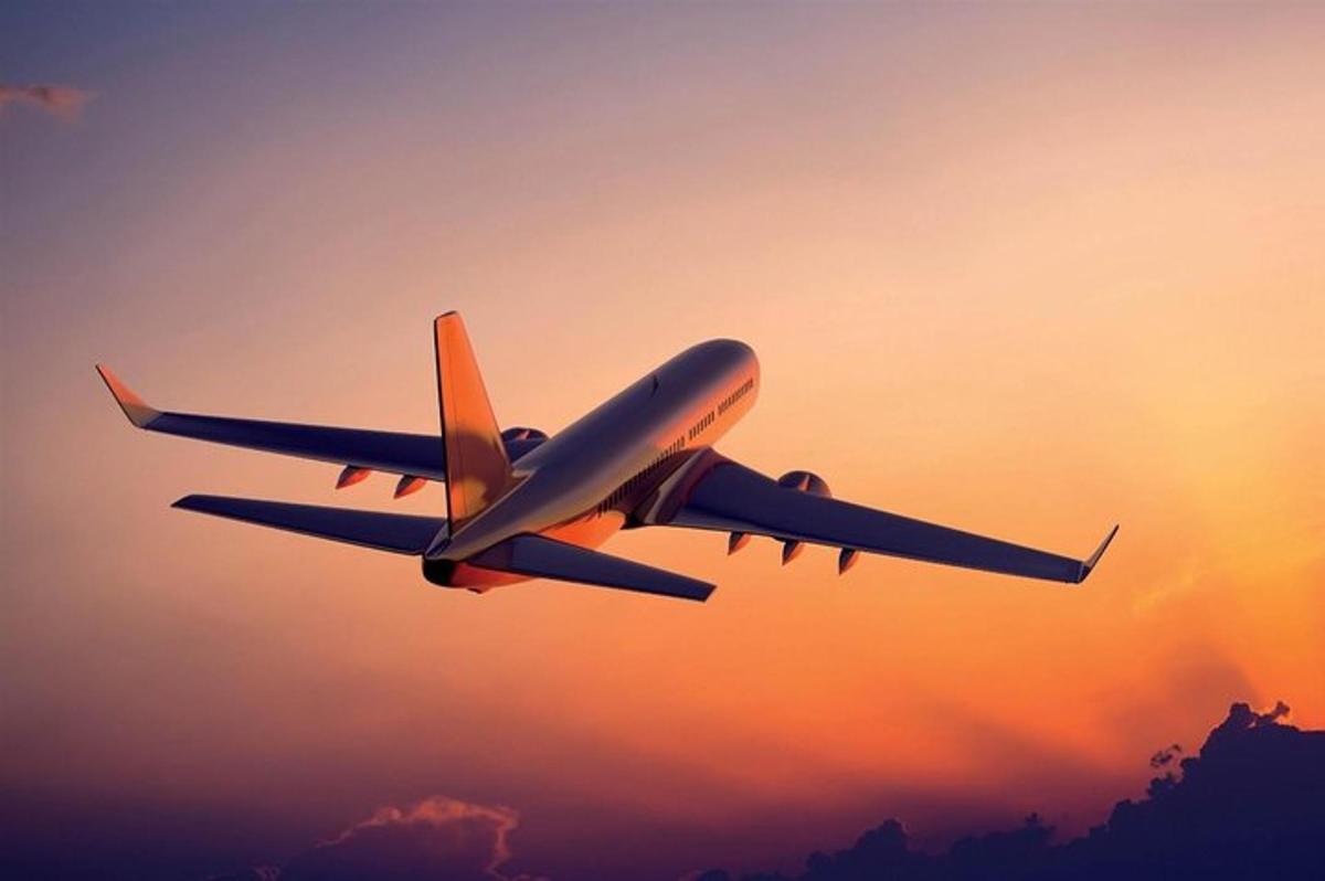 an airplane flying in the sky at sunset