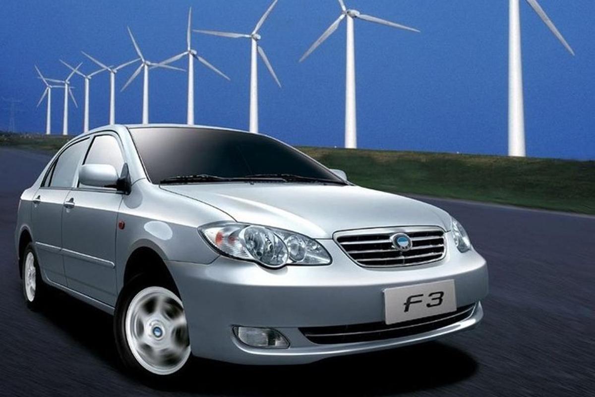 a silver car driving on a road with windmills