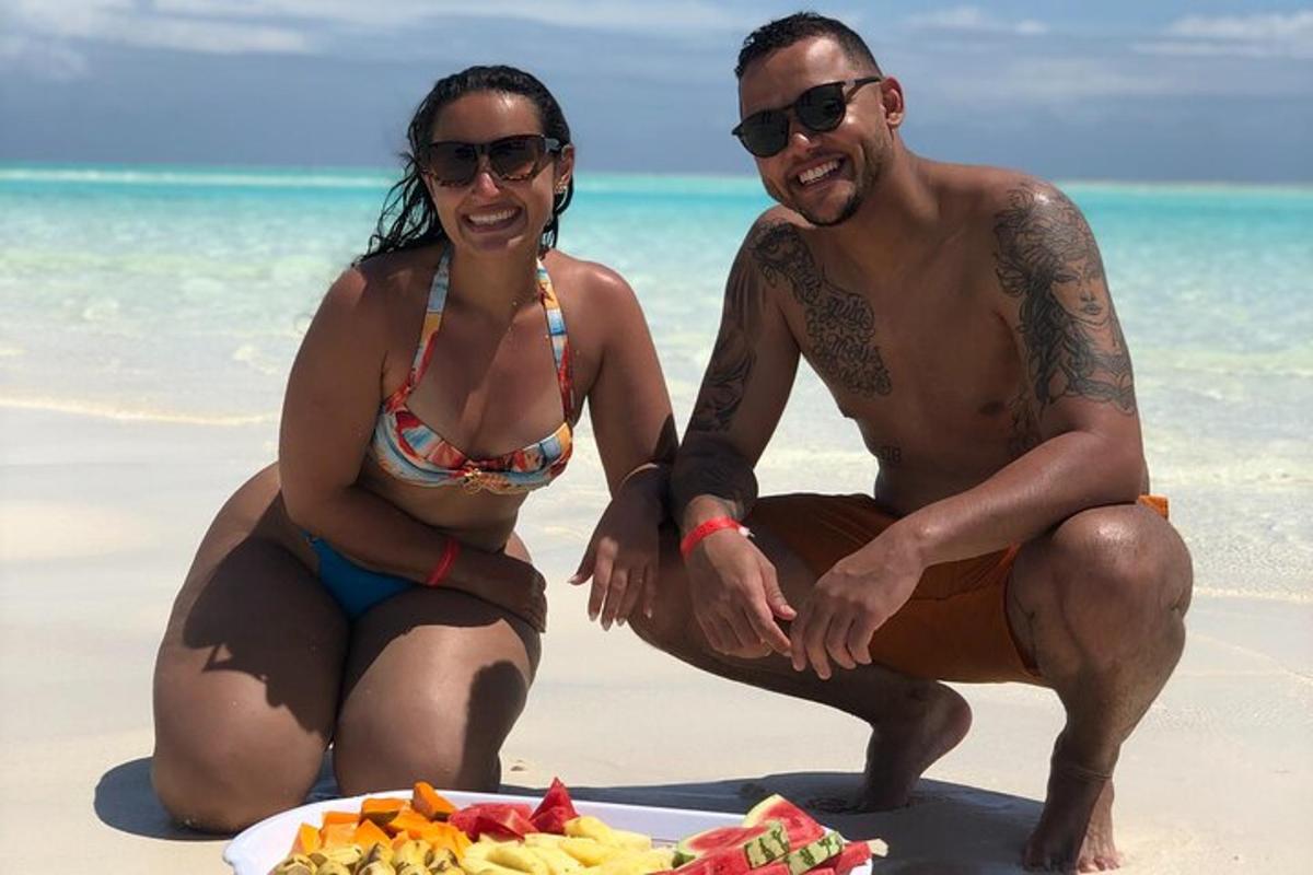 un uomo e una donna seduti sulla spiaggia con un piatto di cibo