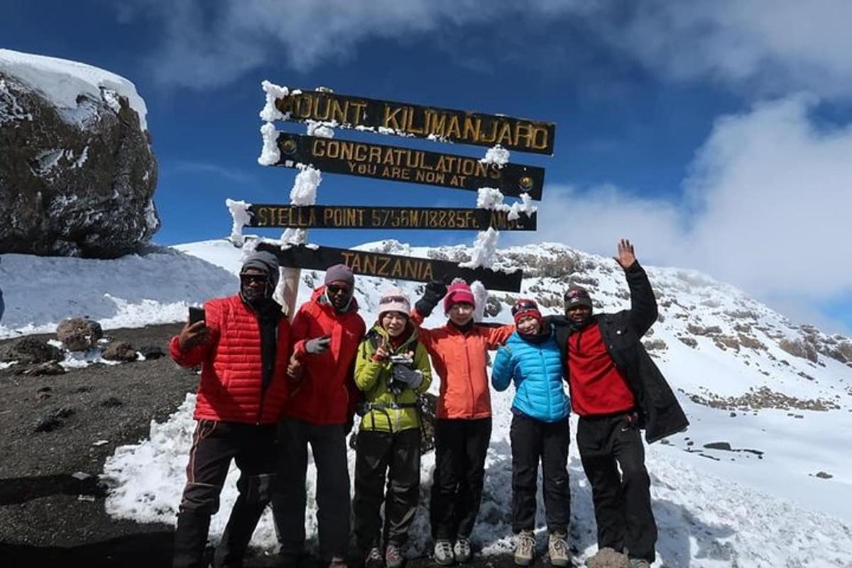 un gruppo di persone in piedi davanti a un cartello su una montagna