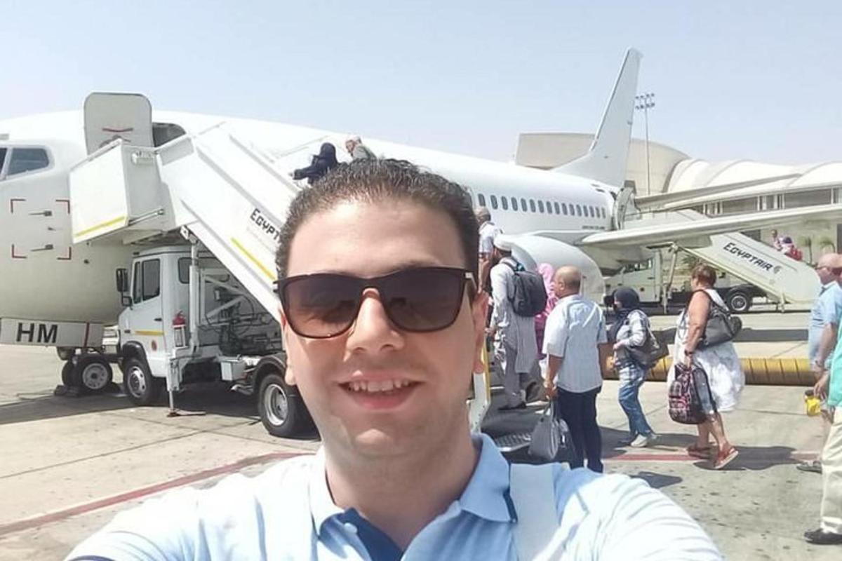 un uomo con occhiali da sole in piedi davanti a un aereo