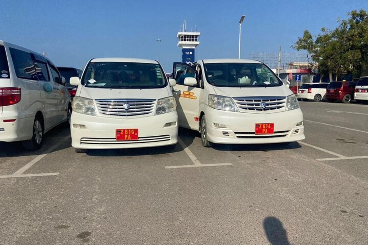 tre hvite biler parkert på en parkeringsplass