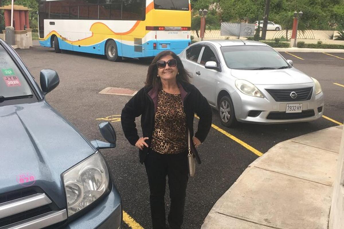 una donna in piedi in un parcheggio accanto a un autobus