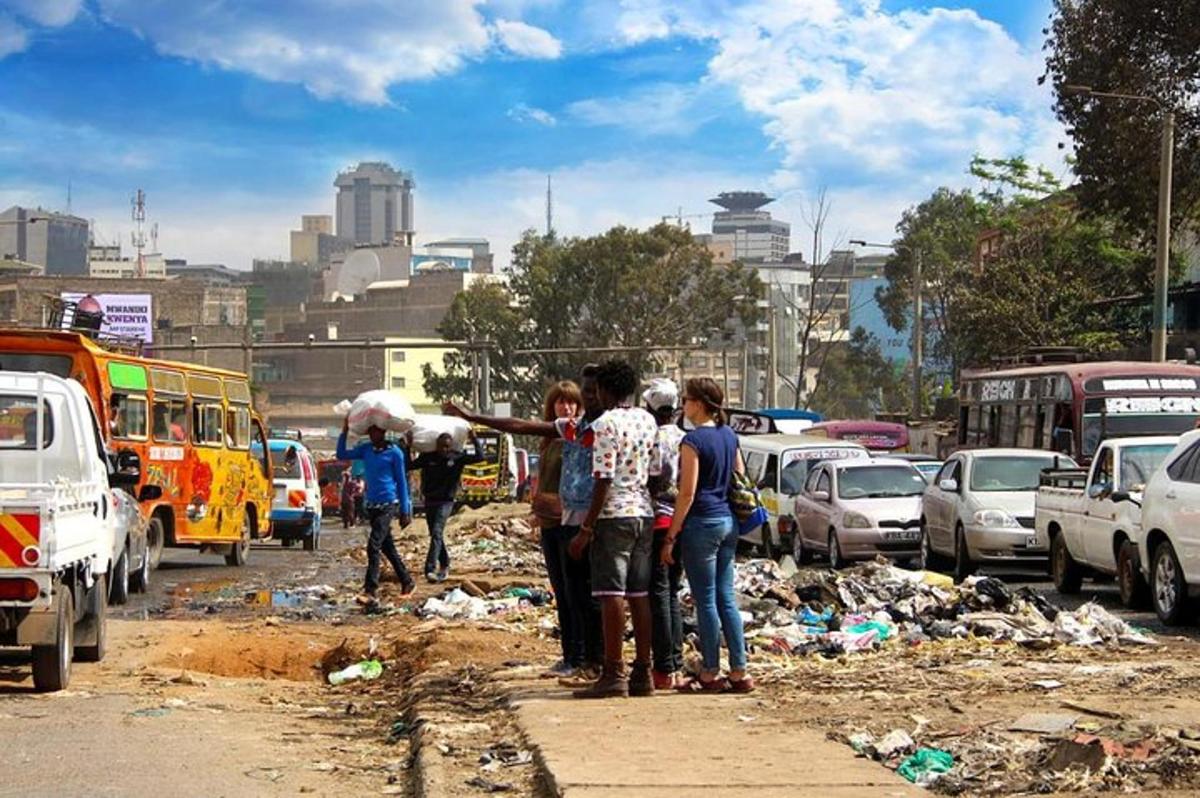 um grupo de pessoas em pé sobre uma pilha de lixo na rua