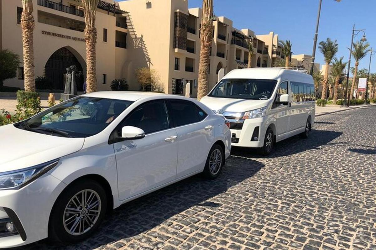 to hvite biler parkert på en gate ved siden av en bygning