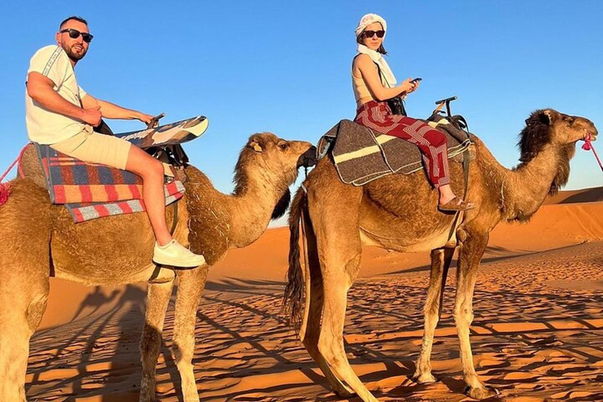 two people riding on camels in the desert