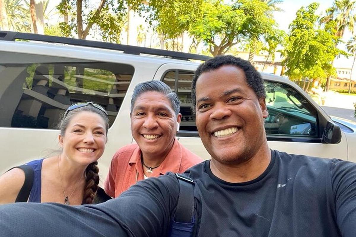 Un grupo de tres personas de pie en la parte trasera de un camión.