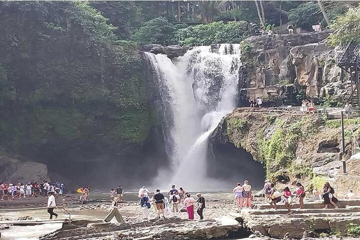 um grupo de pessoas em pé em frente a uma cachoeira