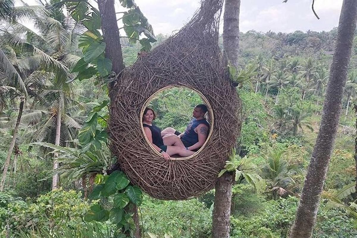 um homem e uma mulher sentados em um ninho em uma árvore