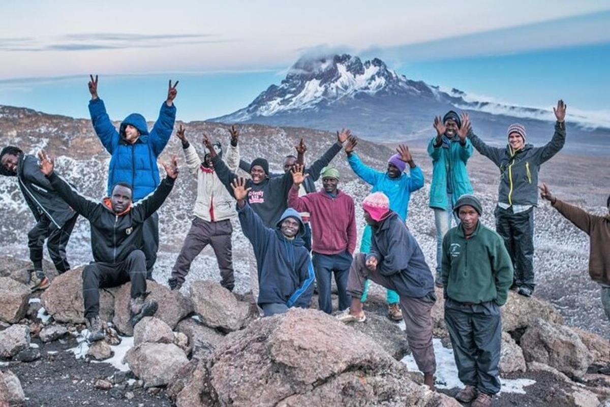 a group of people standing on rocks in front of a mountain