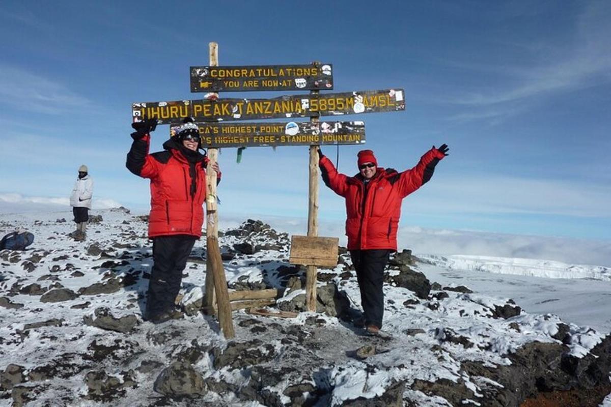 dua lelaki berdiri di sebelah papan tanda di atas gunung