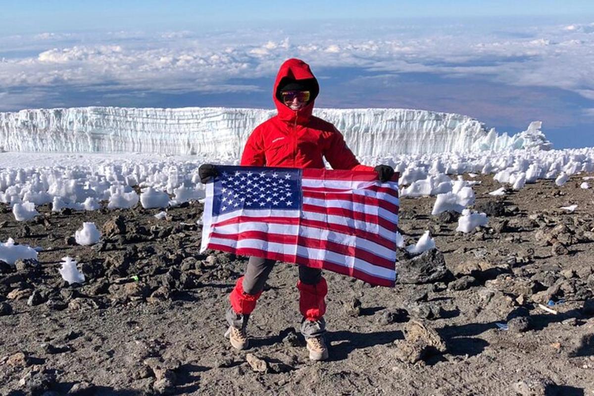 a person holding an american flag on top of a glacier