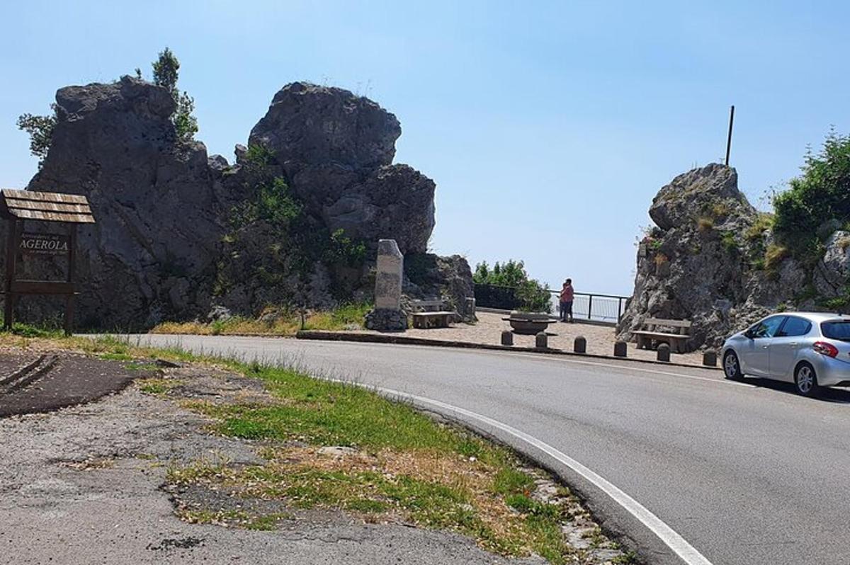 auto jedoucí po silnici vedle skal