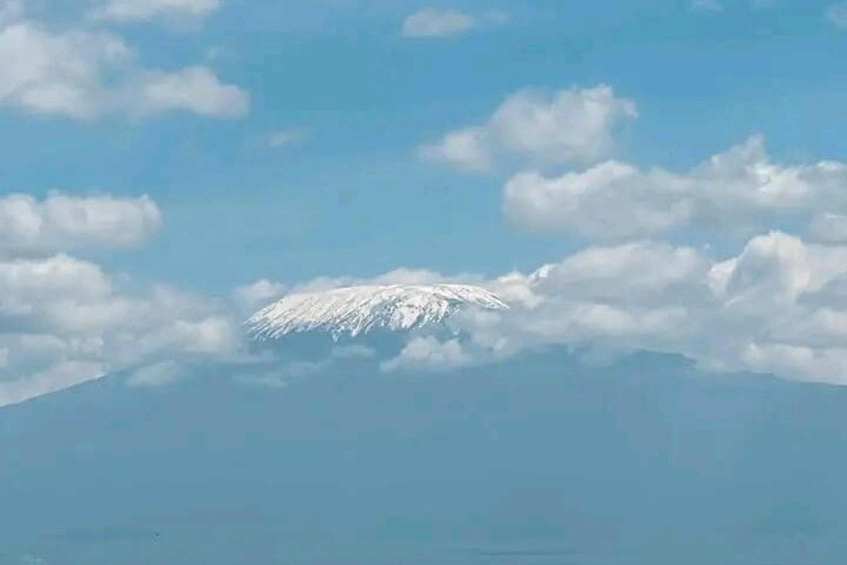 uma montanha coberta de neve no céu com nuvens