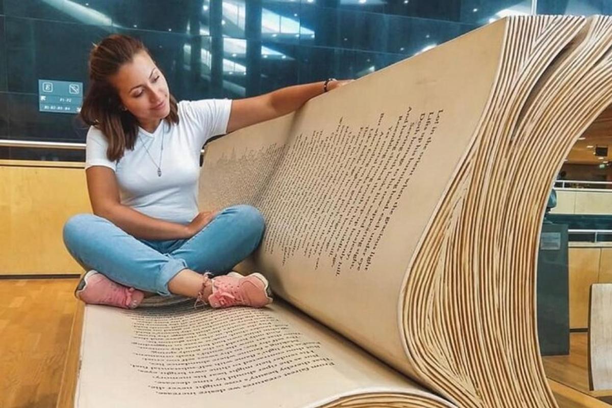 a woman is sitting on a large book