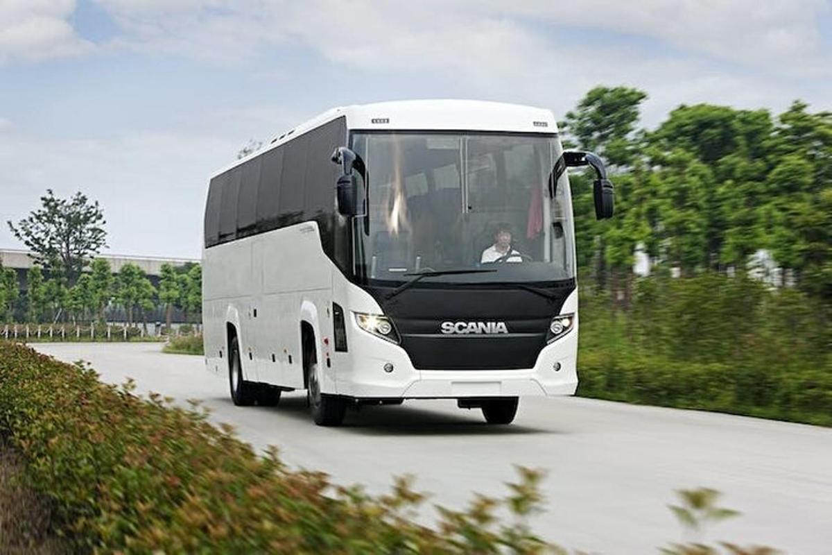 a white bus is driving down a road
