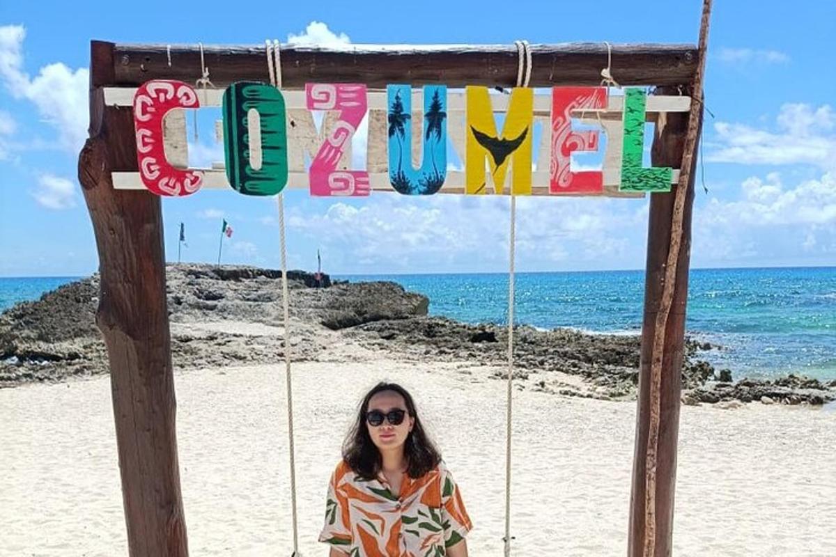 una donna in piedi sotto un cartello sulla spiaggia