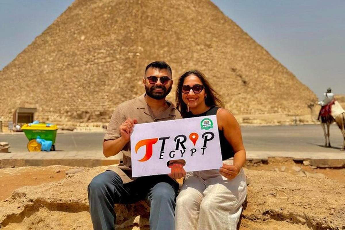 a man and a woman holding a sign in front of the pyramids
