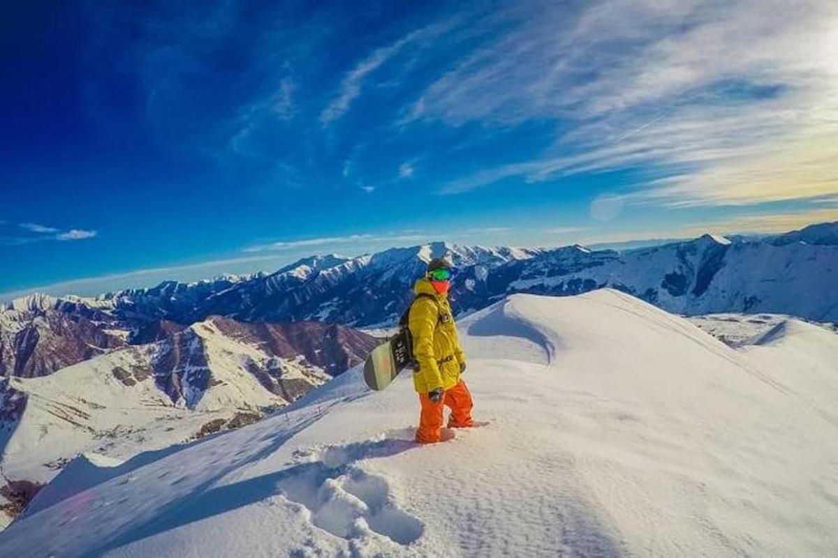 osoba stojící na vrcholu hory se snowboardem