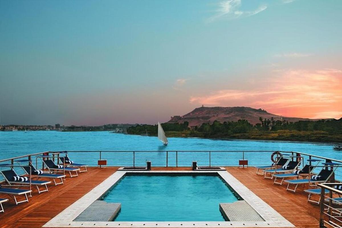 a pool on a cruise ship with chairs and a sailboat