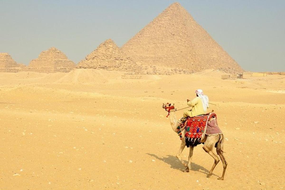 muž jazdiaci na ťave pred pyramídami