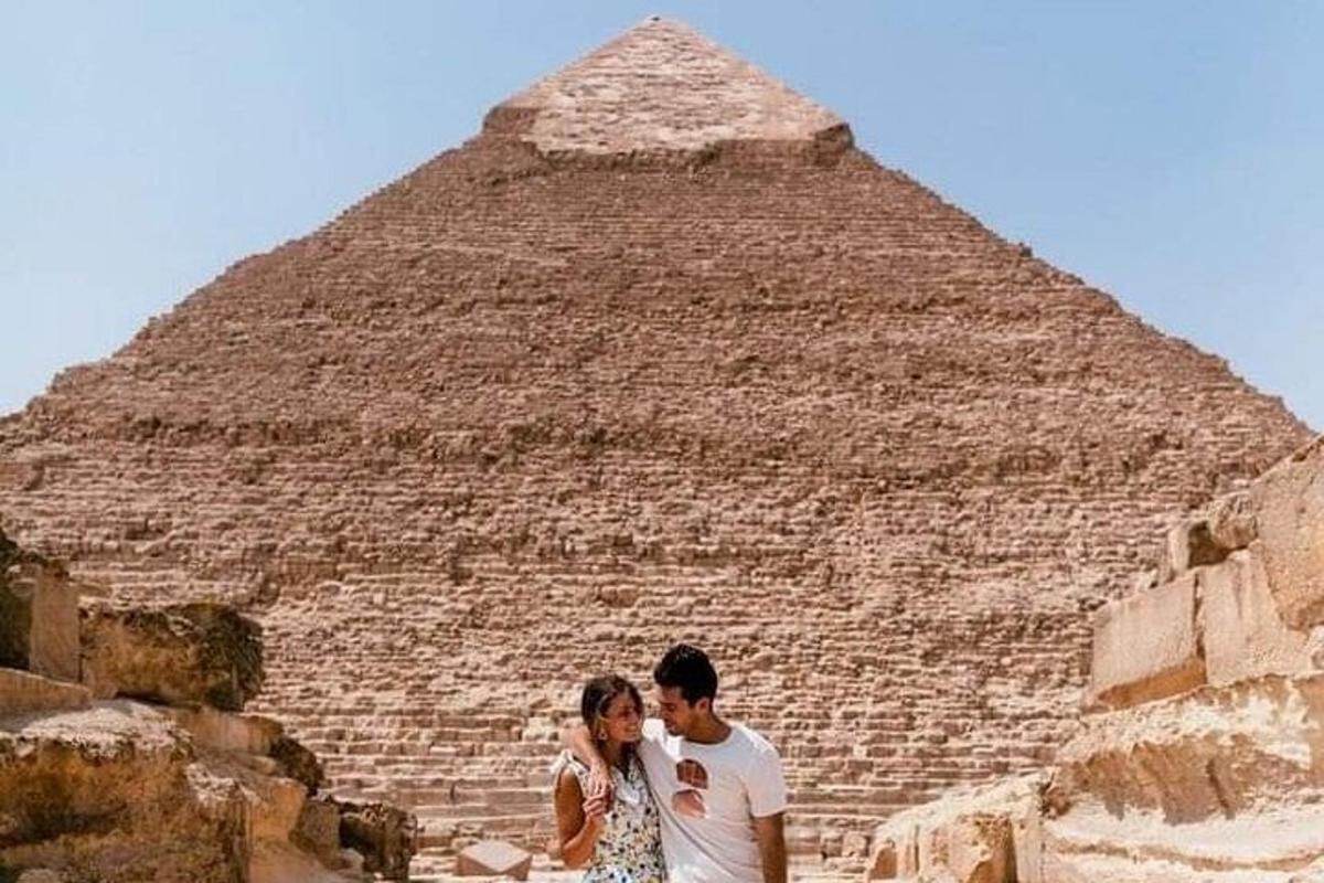 un uomo e una donna in piedi davanti alla piramide