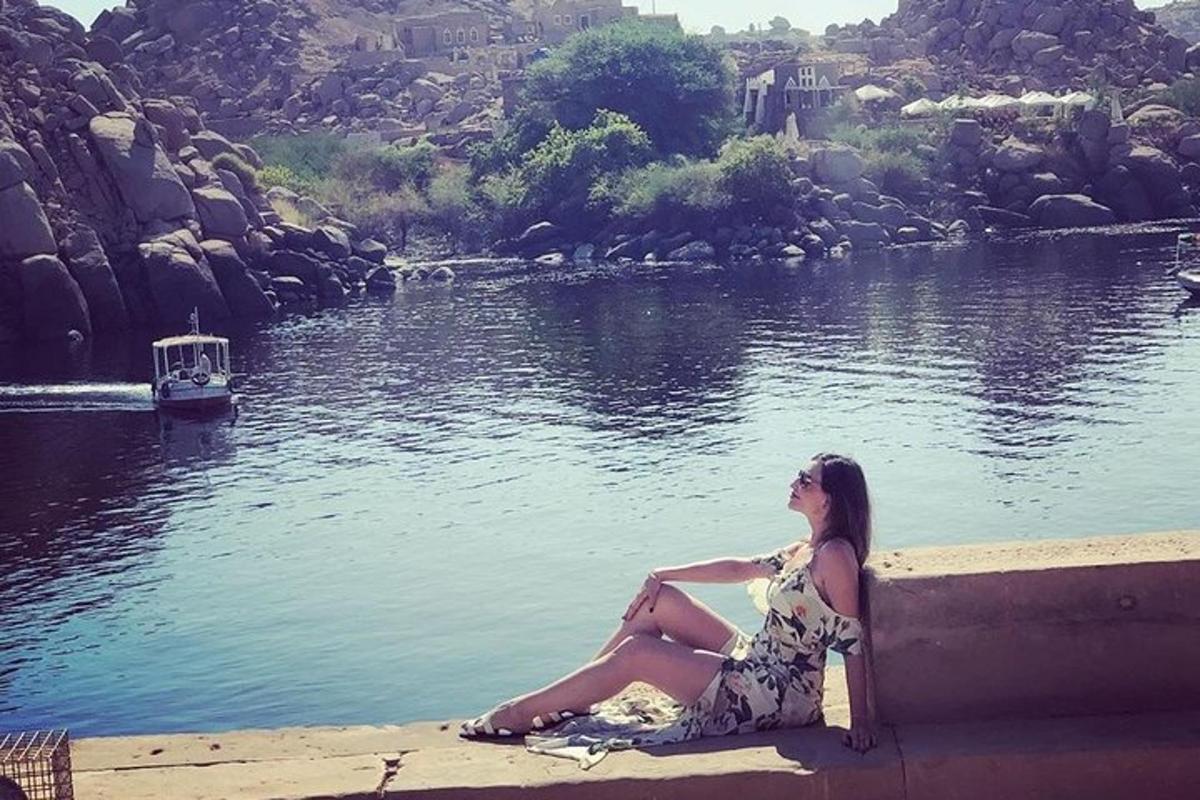 una donna seduta su un muro accanto a uno specchio d'acqua