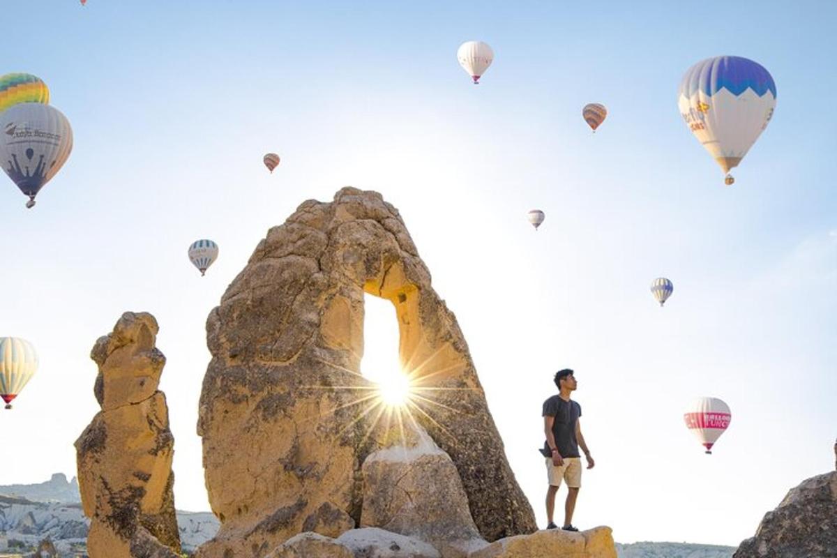 un uomo in piedi su una roccia con mongolfiere