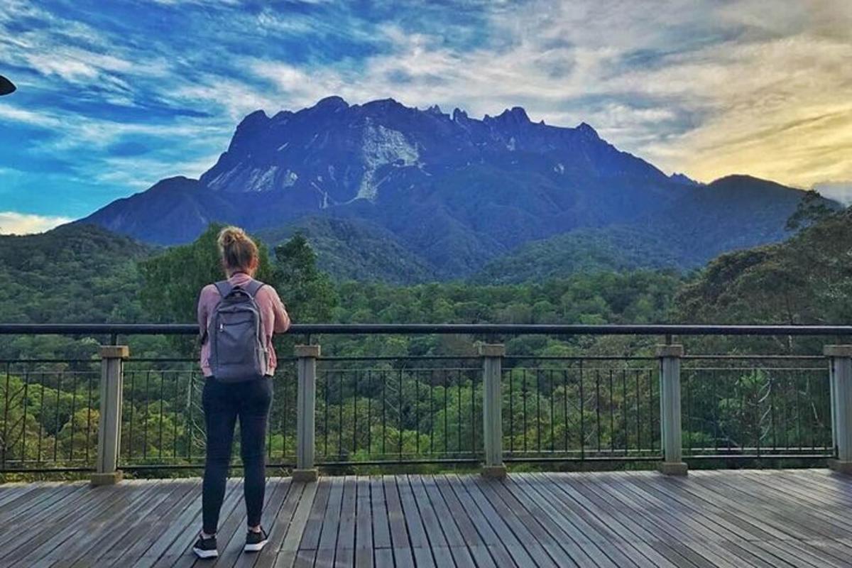 dívka stojící na dřevěné terase a dívající se na horu
