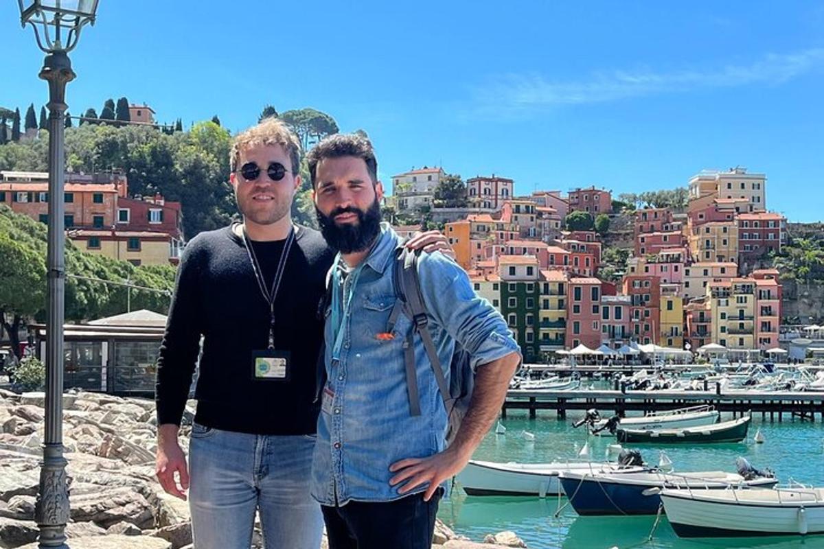 dois homens em pé em frente a um porto com barcos