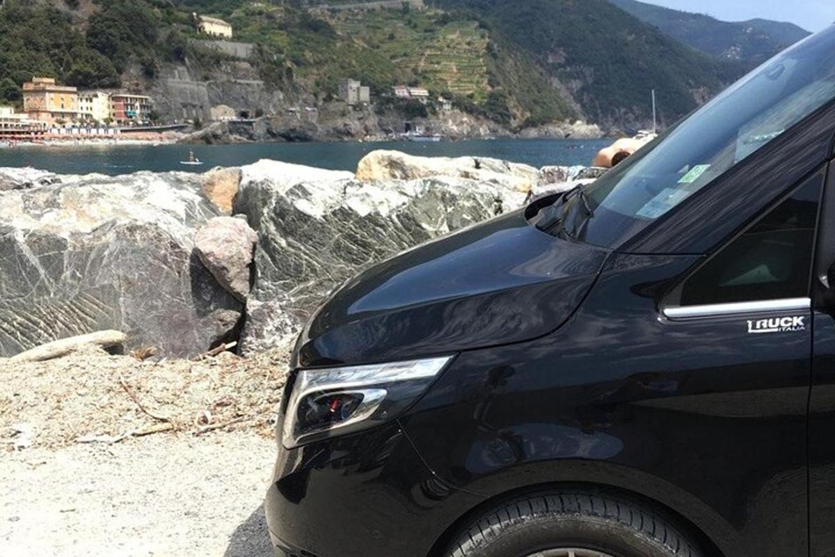 um carro preto estacionado em uma praia perto de um corpo d'água