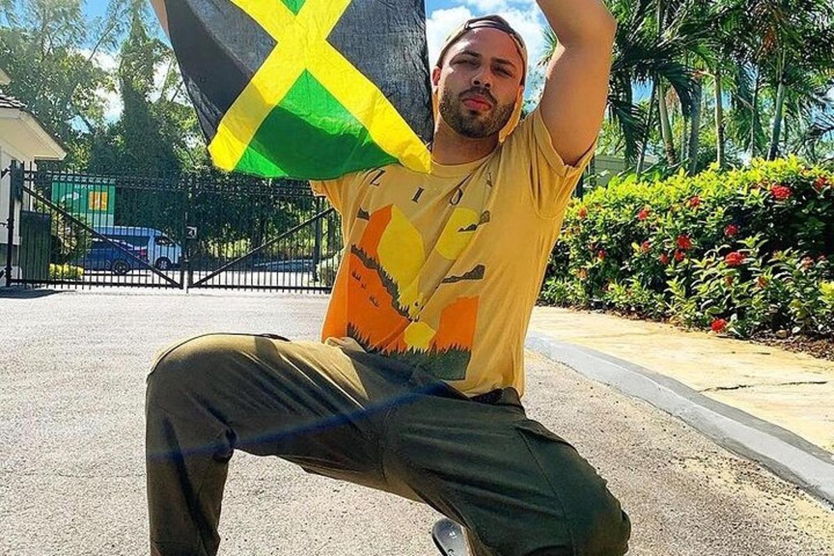 un uomo seduto su uno skateboard che tiene in mano una bandiera