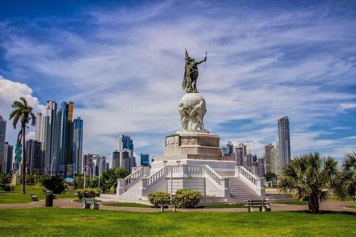 una statua in un parco con una città sullo sfondo