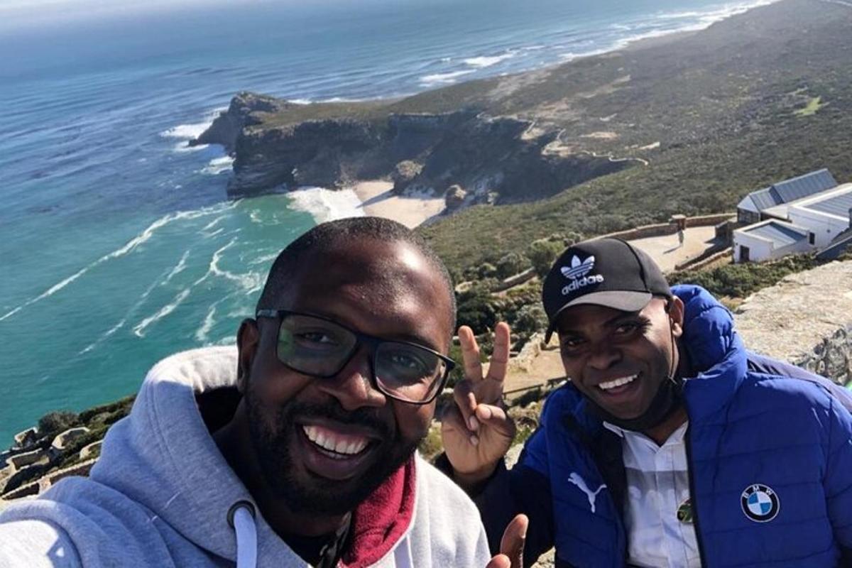 Zwei Männer stehen auf einem Berggipfel mit Blick auf das Meer