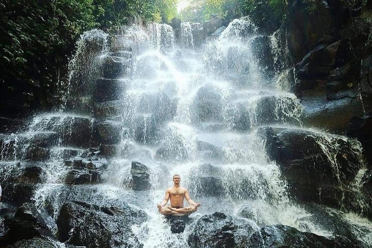 um homem sentado em frente a uma cachoeira