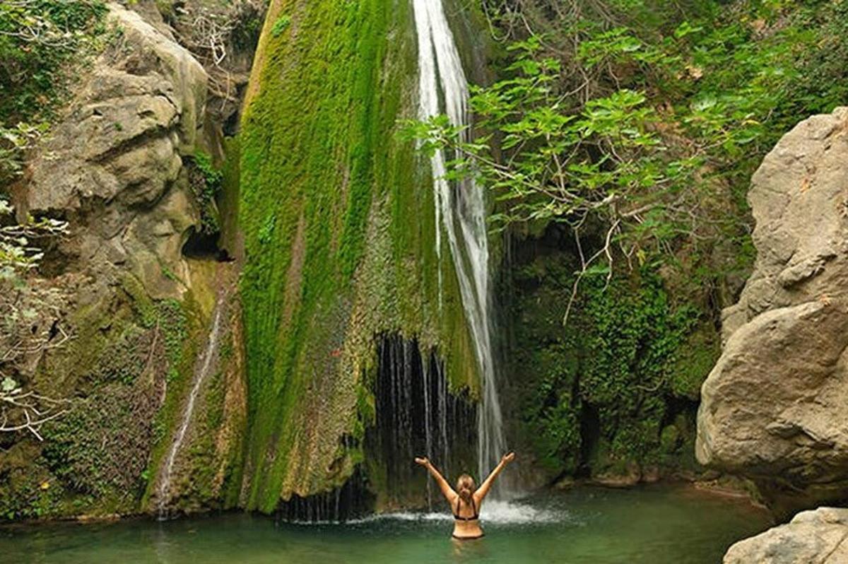 seorang wanita berdiri di dalam air di hadapan air terjun