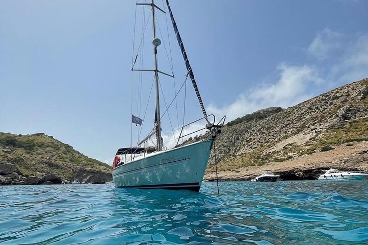 um barco parado na água ao lado de uma colina