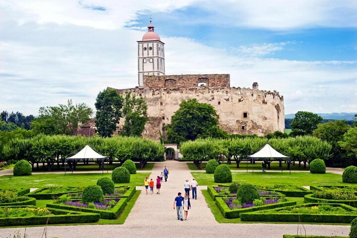 Un grupo de personas caminando por un jardín frente a un castillo.