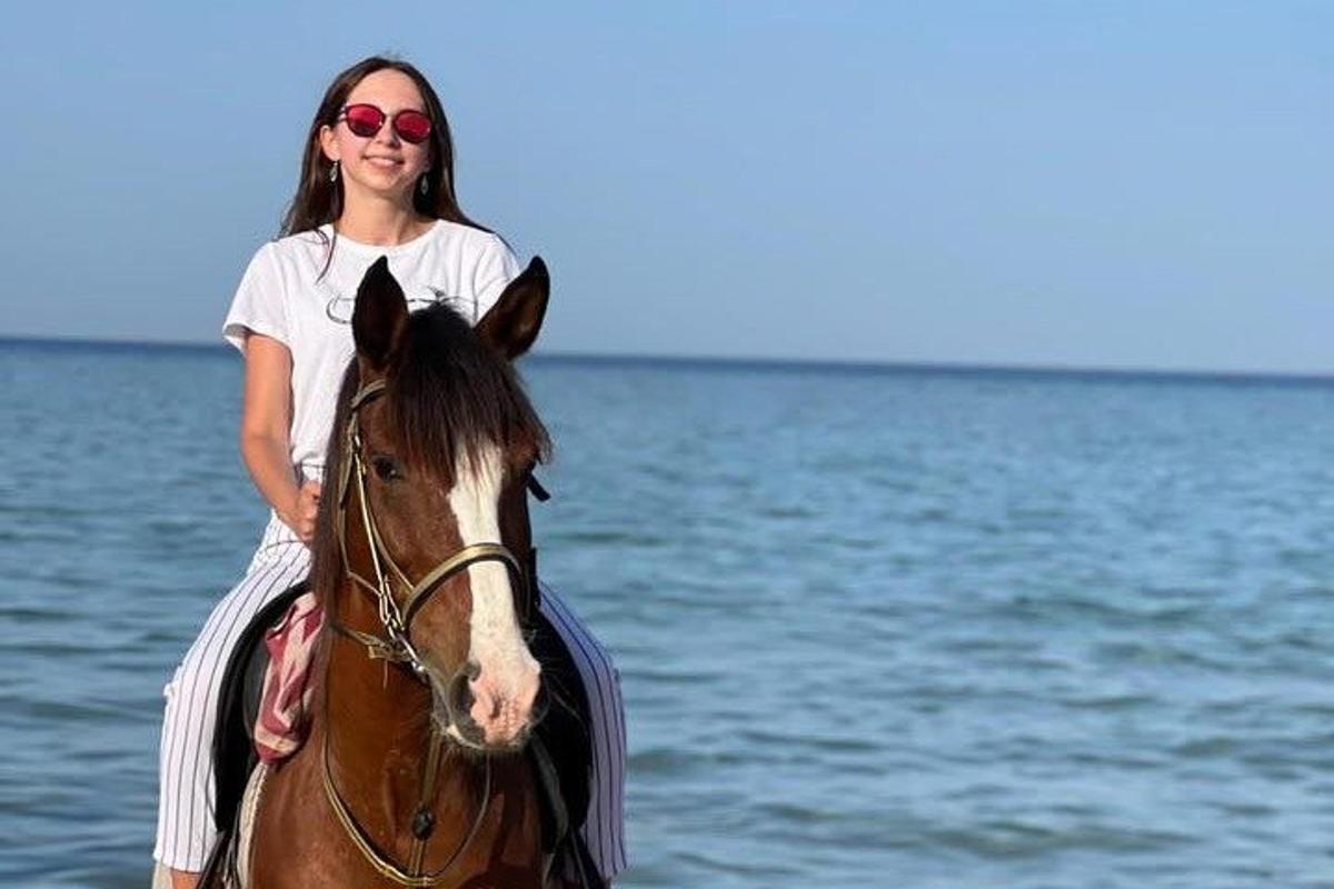 žena jazdiaca na koni vo vode