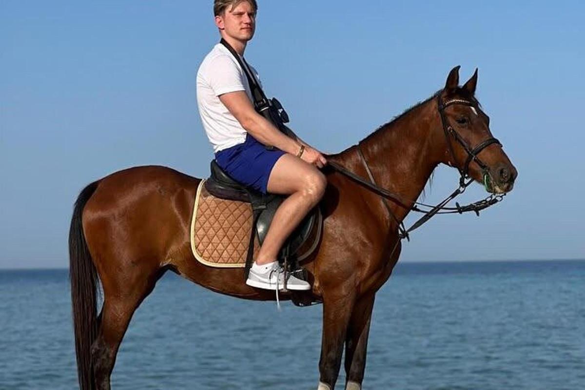 muž jazdiaci na koni na pláži