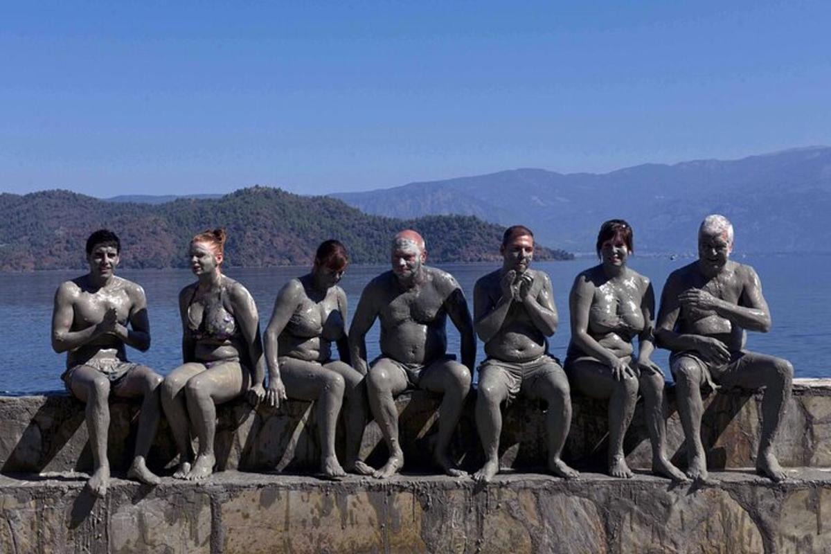 un gruppo di uomini nudi seduti su un muro vicino all'acqua