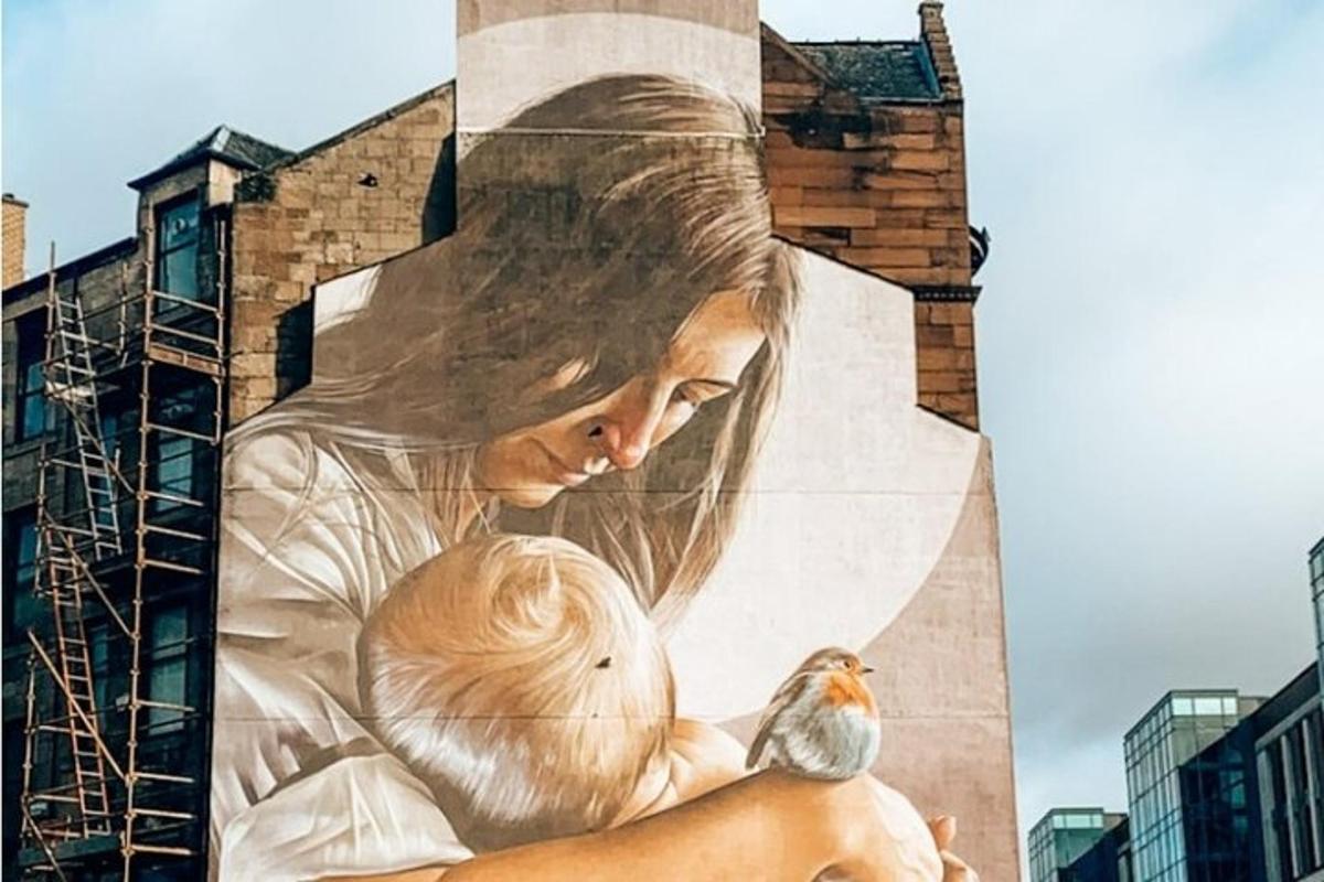 Un mural de una mujer sosteniendo un bebé y un pájaro.