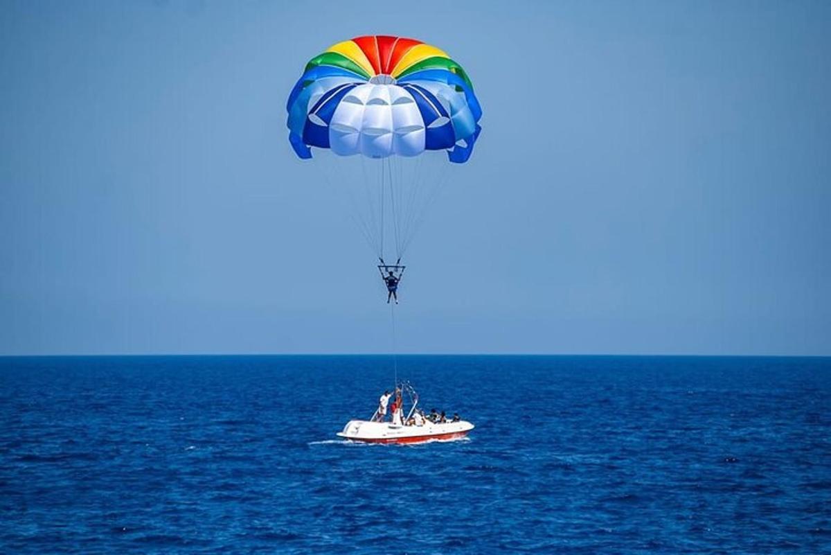 o parașută colorată zburând deasupra unei bărci în ocean